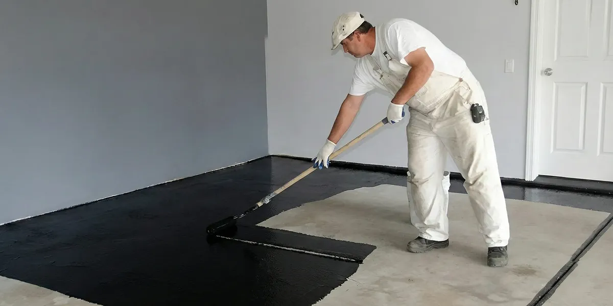 basement waterproofing professional applying waterproof coating to protect a basement floor in Columbus, OH